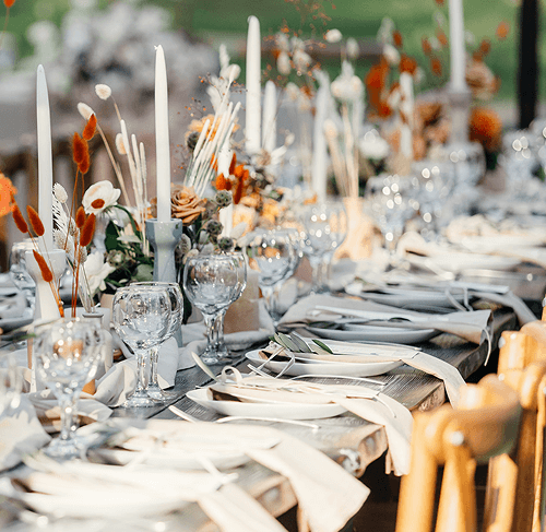 Svadobná hostina s rustikálnou kvetinovou výzdobou, sviečkami a&nbsp;elegantne prestretým stolom.