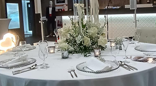 Elegantne prestretý svadobný stôl s bielymi kvetmi a&nbsp;sviečkami v Azul Restaurant